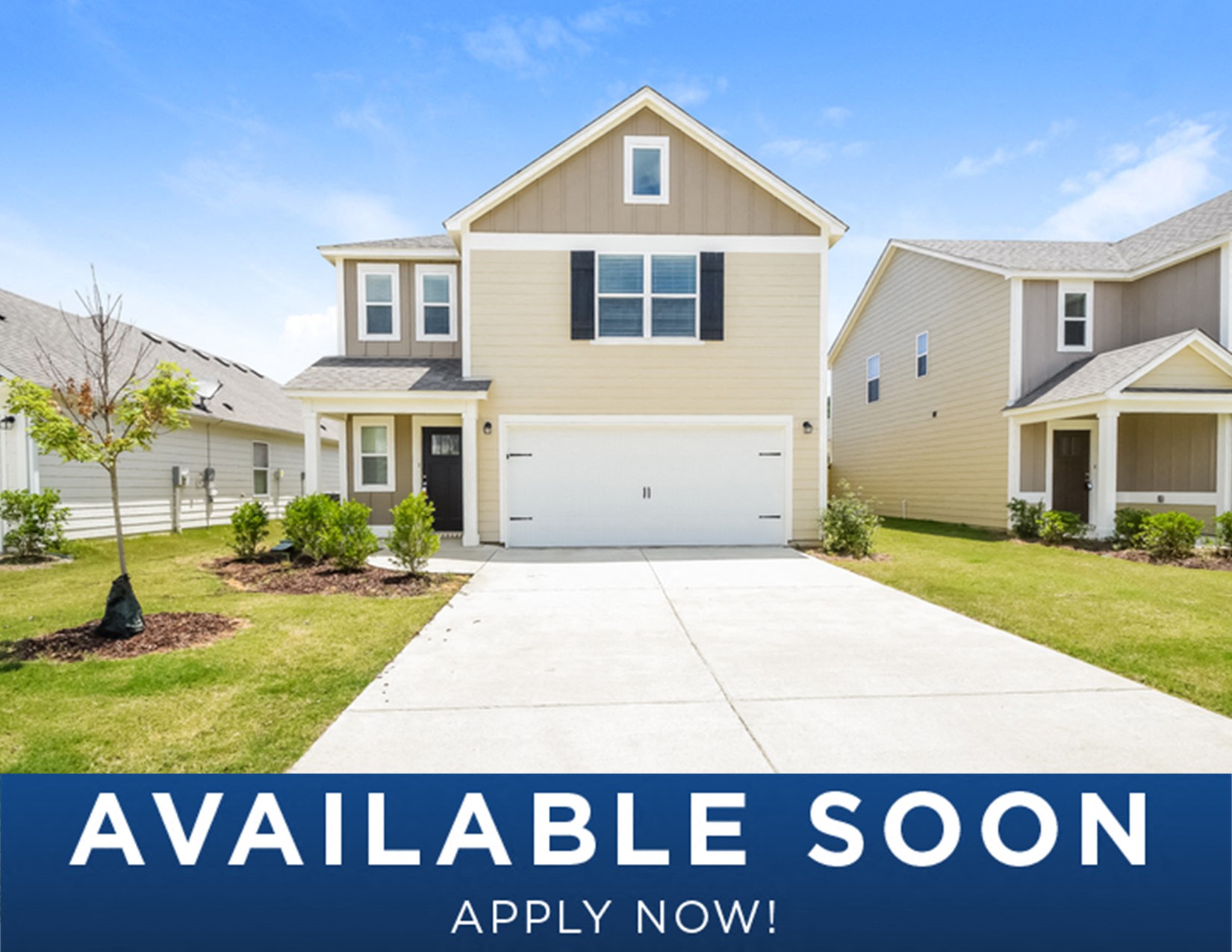 a beige and tan house on a lawn with a driveway
