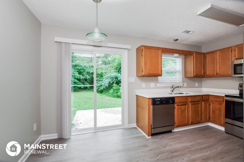 a kitchen with wooden cabinets and a sliding glass door to the yard