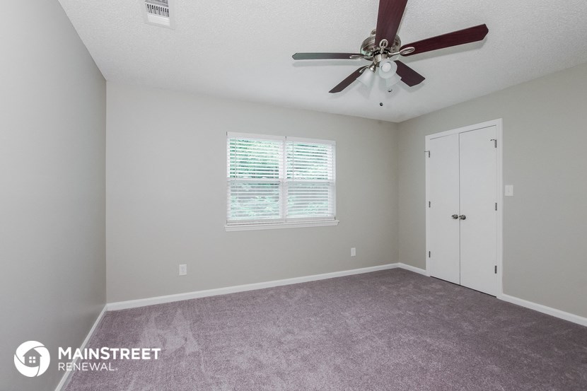 the master bedroom has a carpeted floor and a ceiling fan