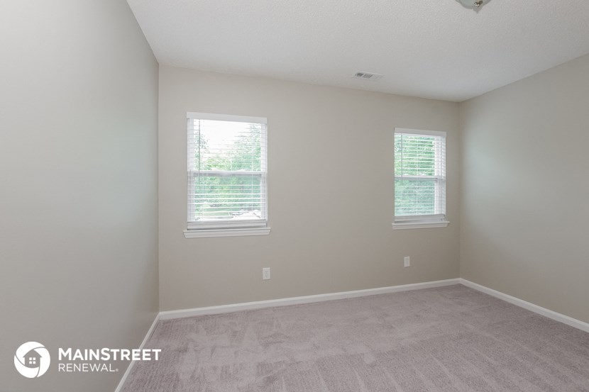 a room with a carpeted floor and two windows