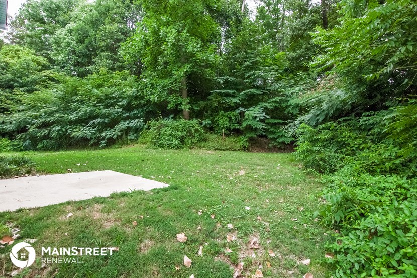 the backyard of a house with a concrete slab in the grass