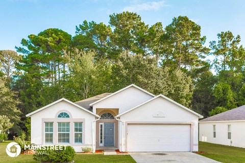 a white house with a garage and trees in the background