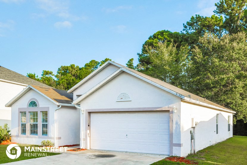 a white house with a white garage door and a lawn