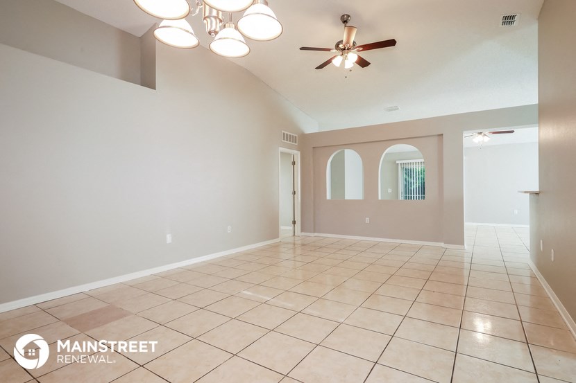the spacious living room with tile flooring and ceiling fan