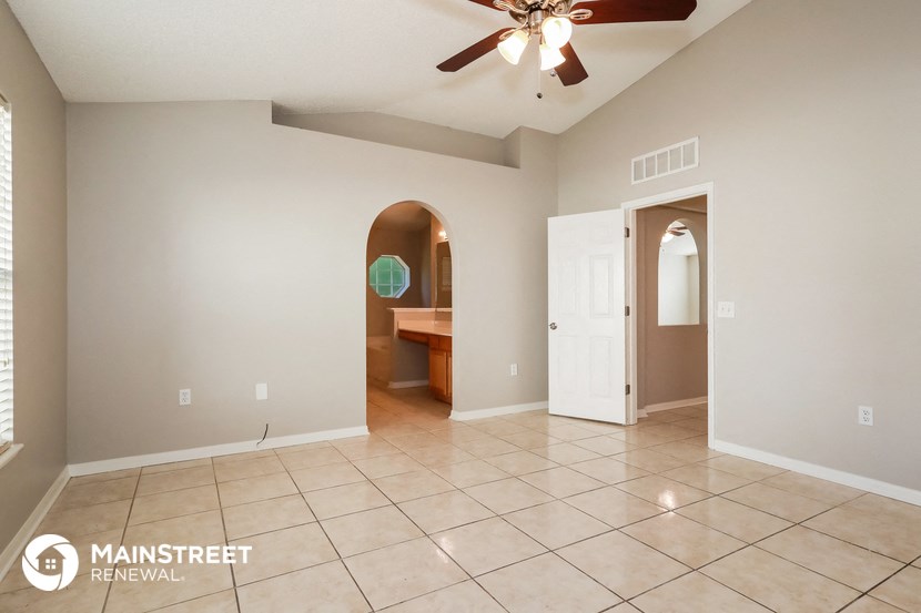 a large living room with tile flooring and a ceiling fan