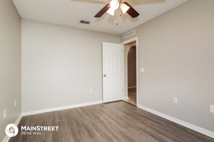 the spacious living room with ceiling fan and hardwood flooring