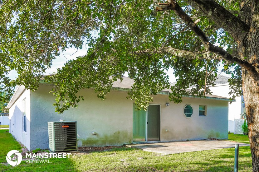 a white house with a green door and a tree