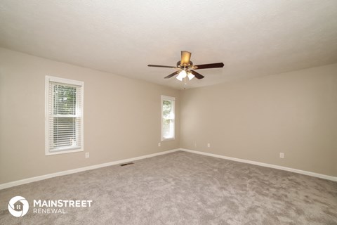 the spacious living room with ceiling fan and carpet