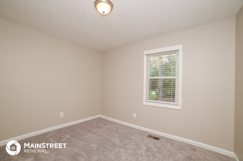 the upstairs bedroom with carpet and a window