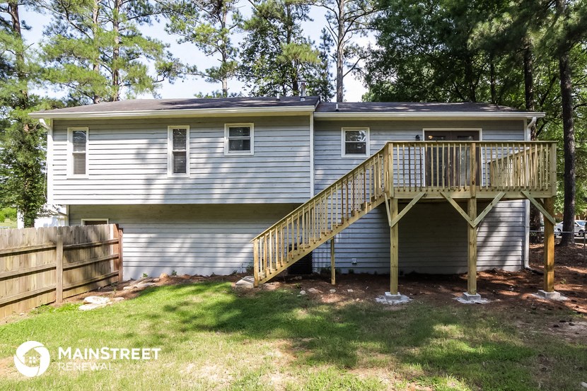 the back of the house with a deck and a wooden fence