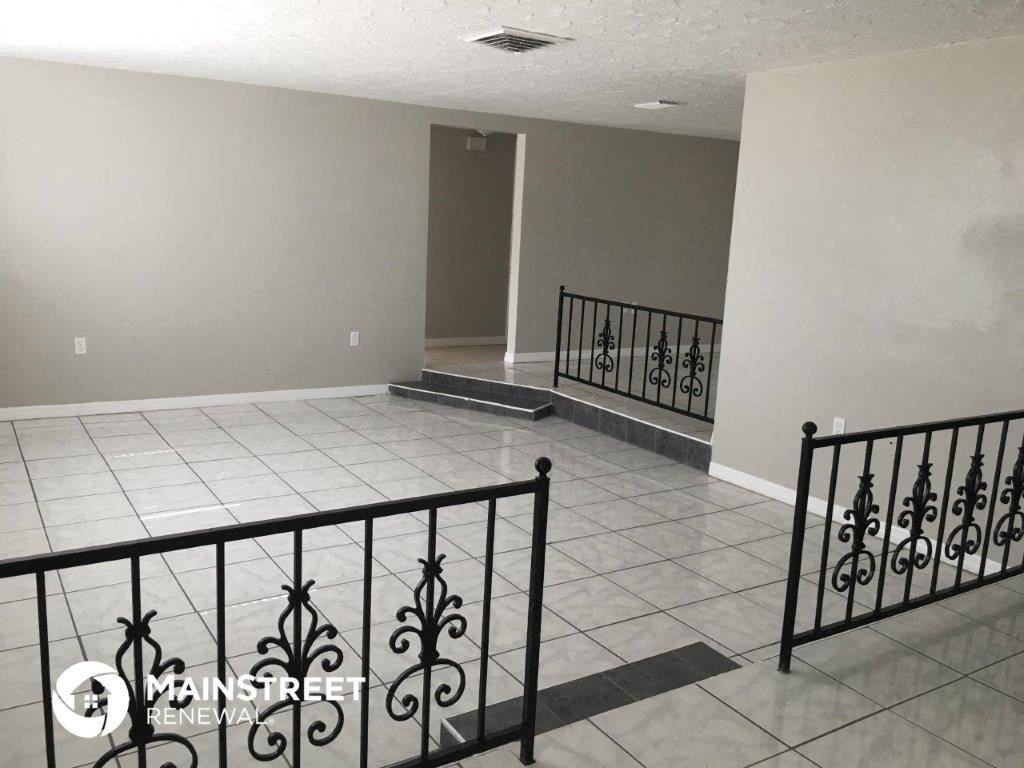a view from the top of the stairs of a house with a tiled floor