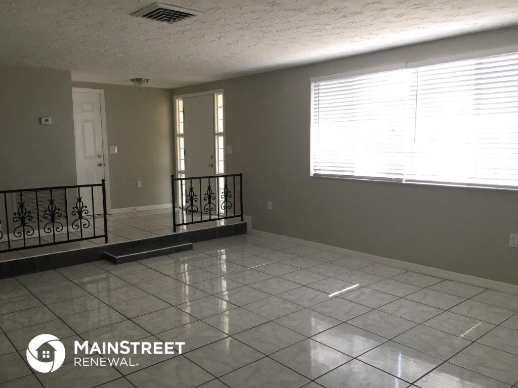 an empty living room with a large tile floor and a window