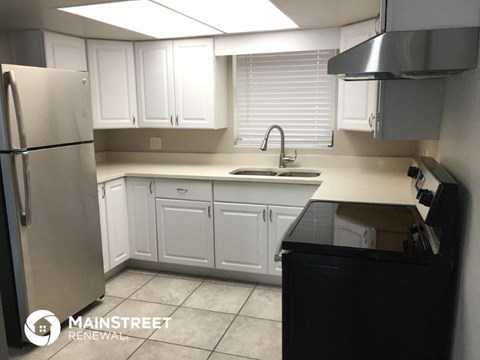 a kitchen with white cabinets and a sink and a refrigerator