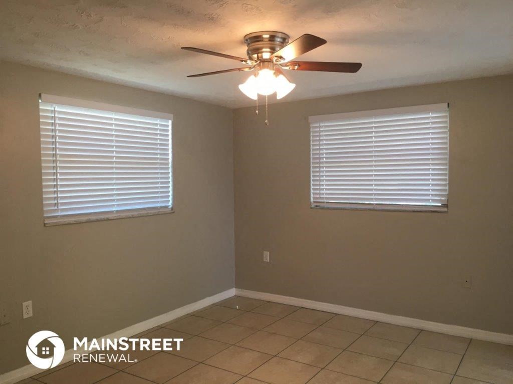 a living room with a ceiling fan and two windows
