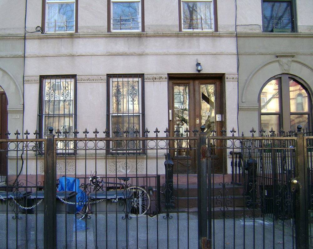 A building with a gate and a bicycle leaning against it.