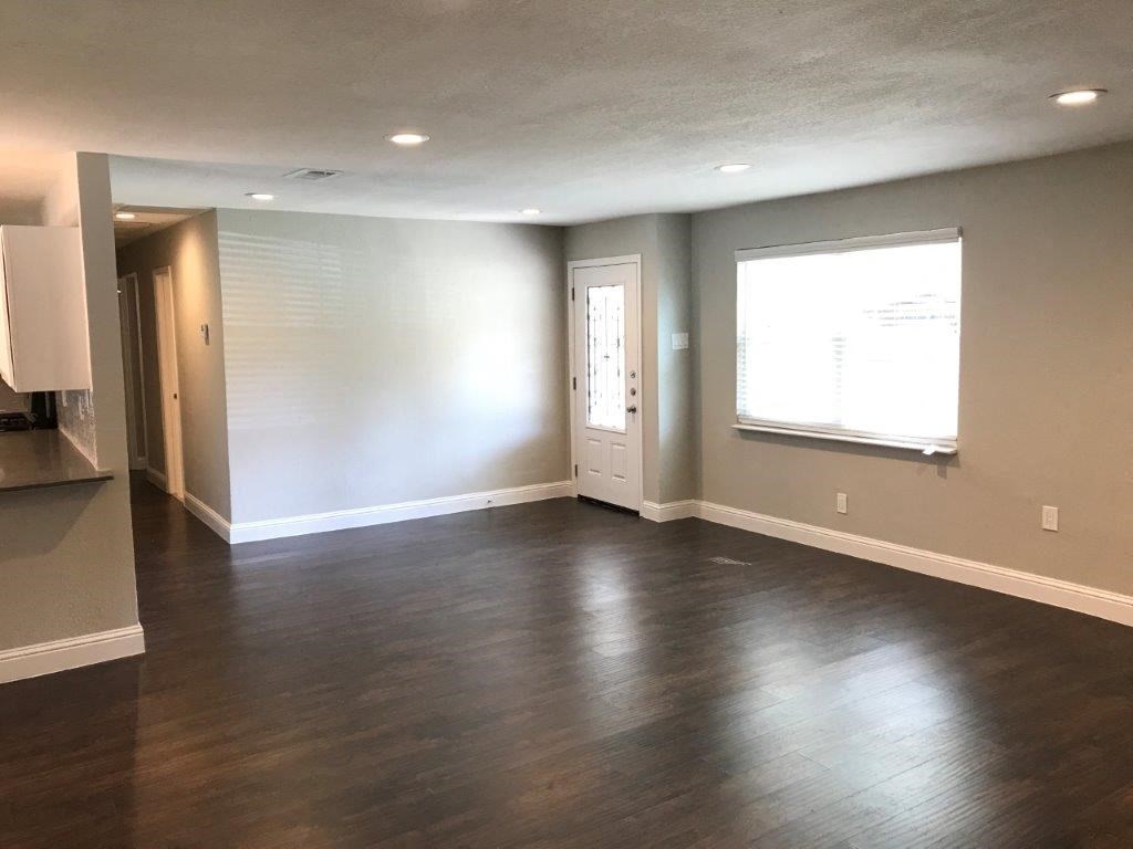 an empty living room with wood floors and a window