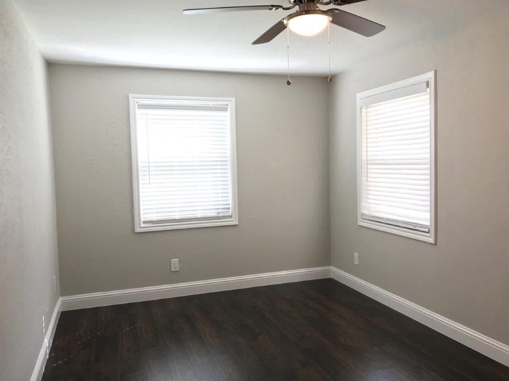 an empty room with wood floors and a ceiling fan