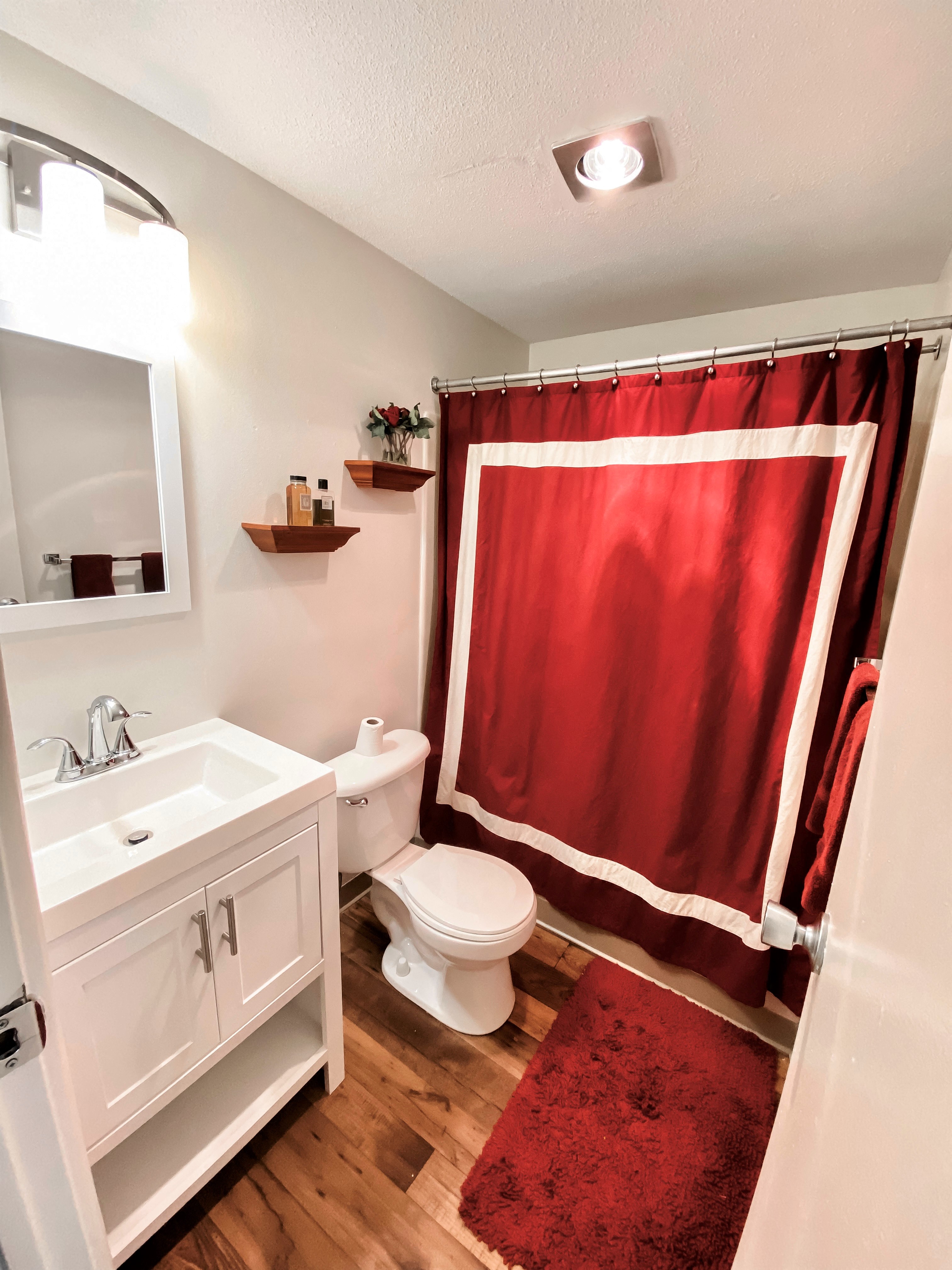a bathroom with a red shower curtain and a white sink