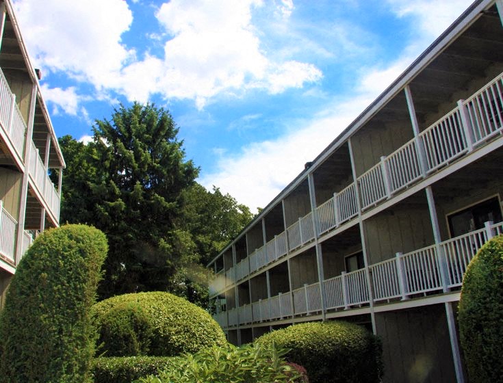 an apartment building with balconies and bushes and trees