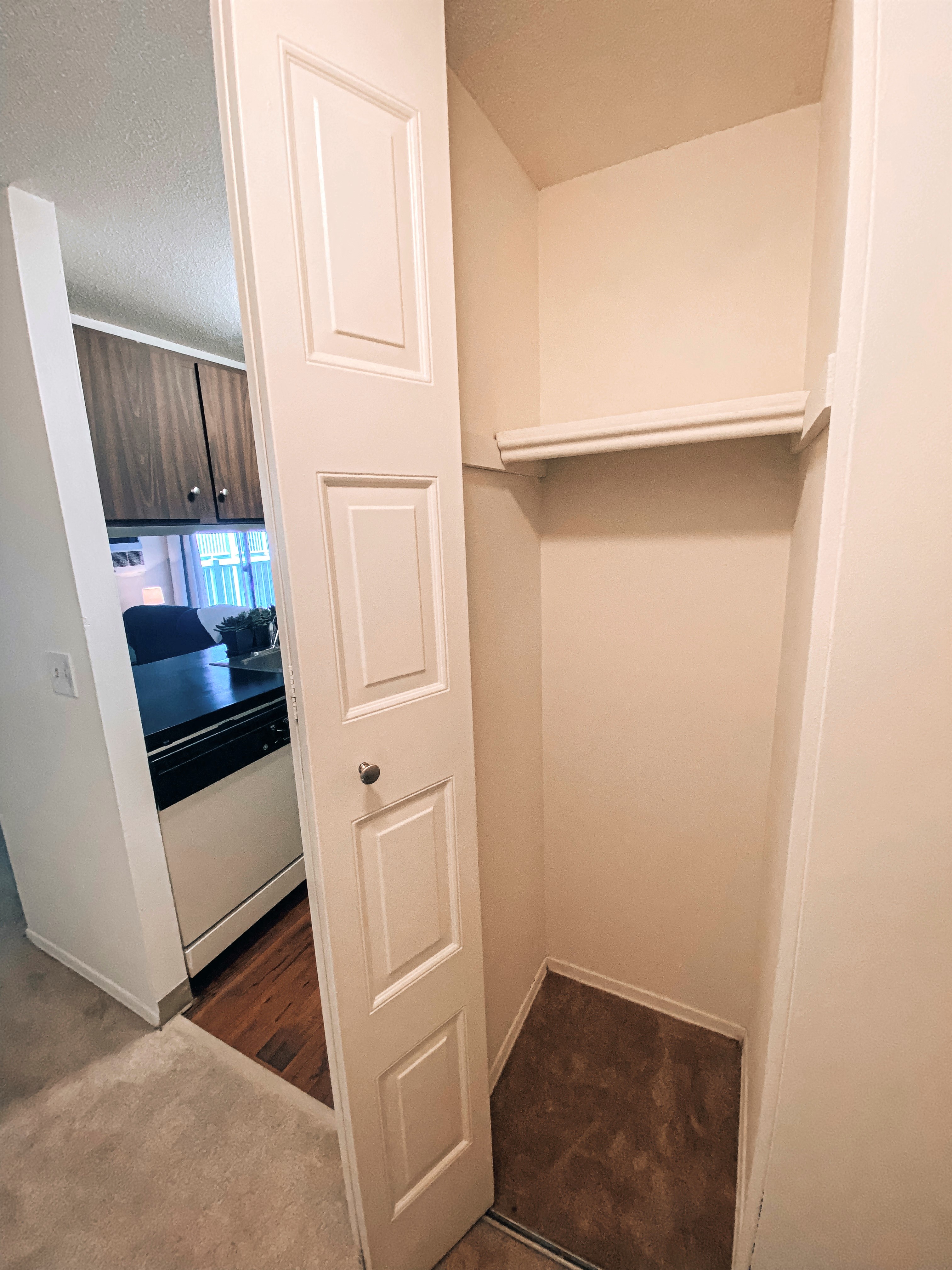 a walk in closet with a door open to a kitchen