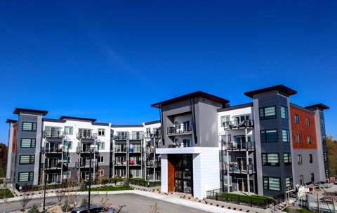 an exterior view of an apartment complex with a blue sky