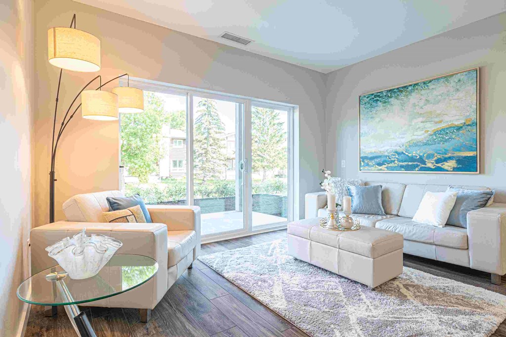 a living room with white furniture and a large painting on the wall