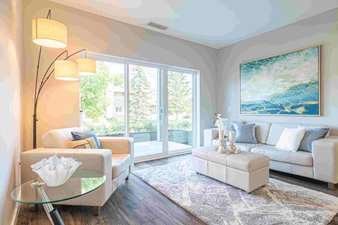 a living room with white furniture and a large painting on the wall