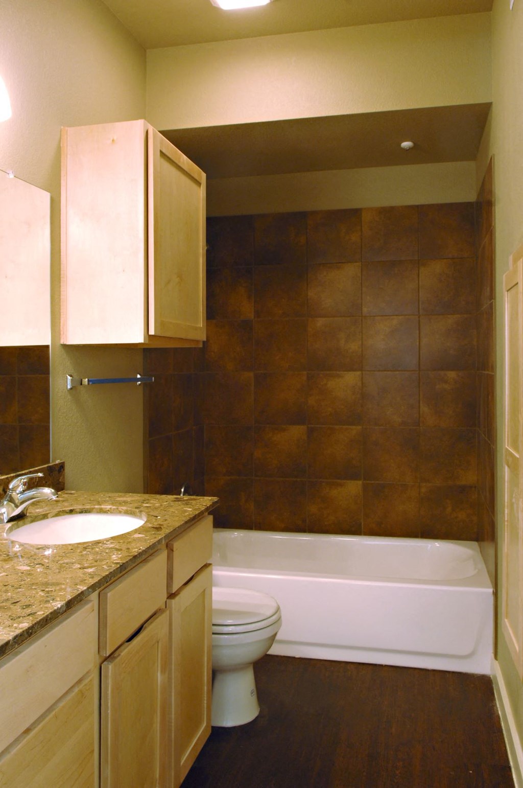 A bathroom with a brown tile wall and a white toilet at Centre Place Apartments, TX, 76205
