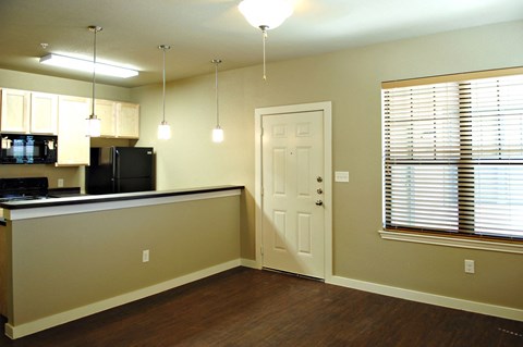 an empty living room with a kitchen and a door