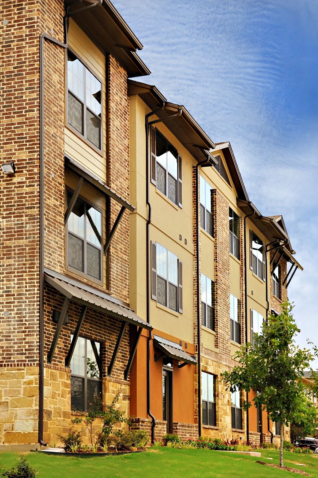 A large building with a brown and tan exterior at Centre Place Apartments, Denton, Texas