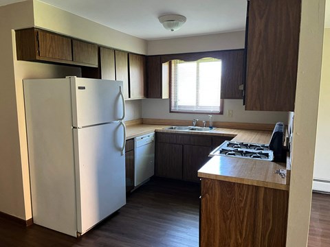 A white refrigerator is in a kitchen with wooden cabinets.