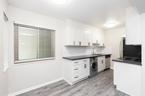 A kitchen with white cabinets and a black countertop.