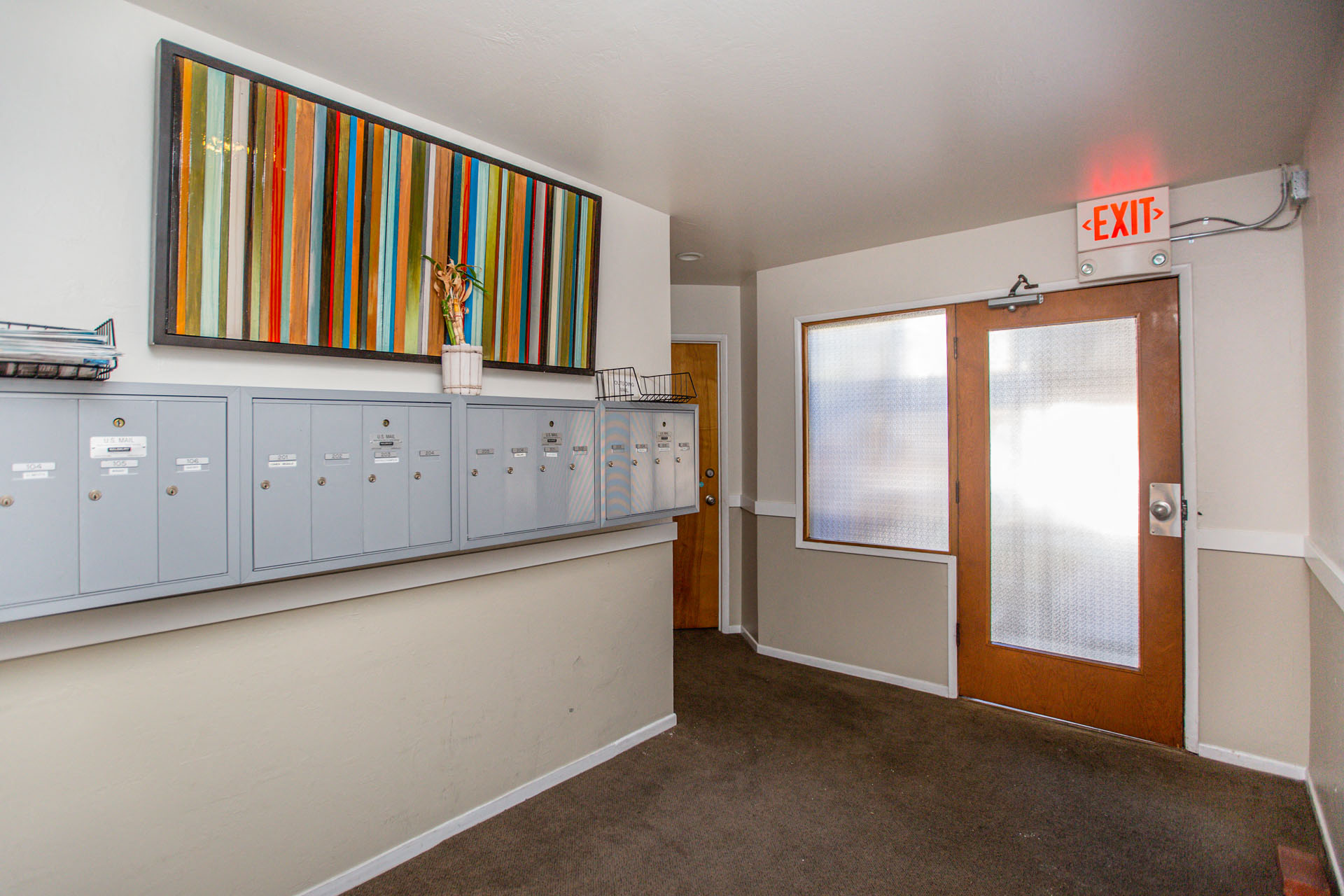 A hallway with a red exit sign above the door.