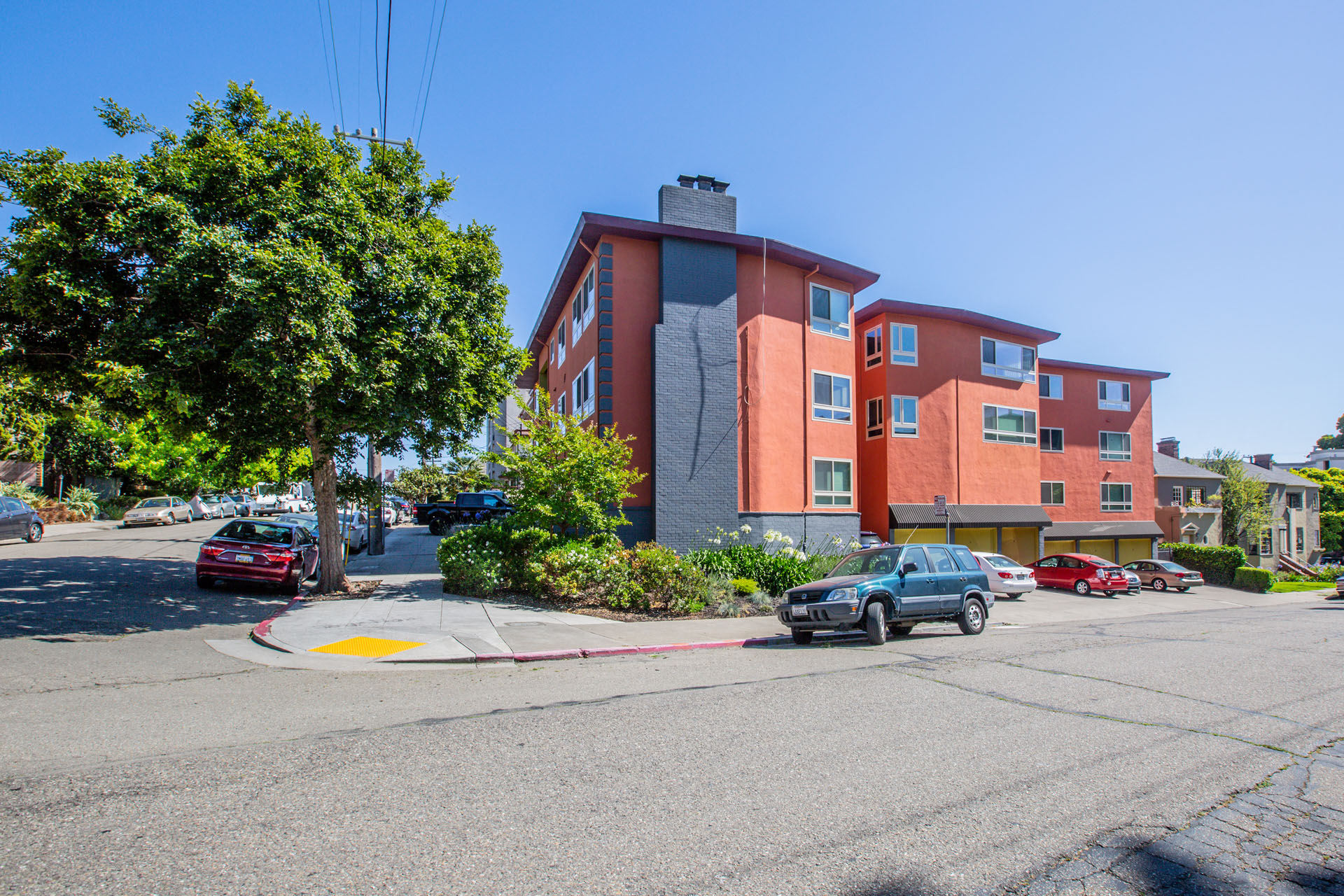 A street view of a red building with cars parked in front.