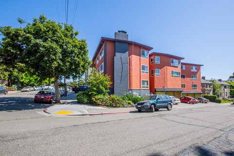 A street view of a red building with cars parked in front.