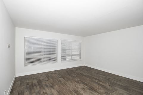 an empty room with white walls and wood flooring and a window