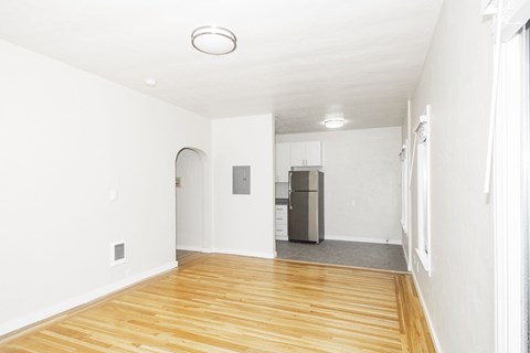 A kitchen area with a refrigerator and a wooden floor.