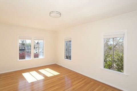 A room with wooden floors and three windows.