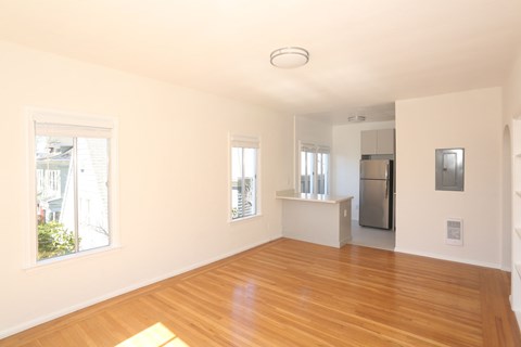 A spacious, empty room with wooden floors and white walls.