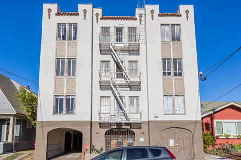 A white building with a red roof and a car parked in front.