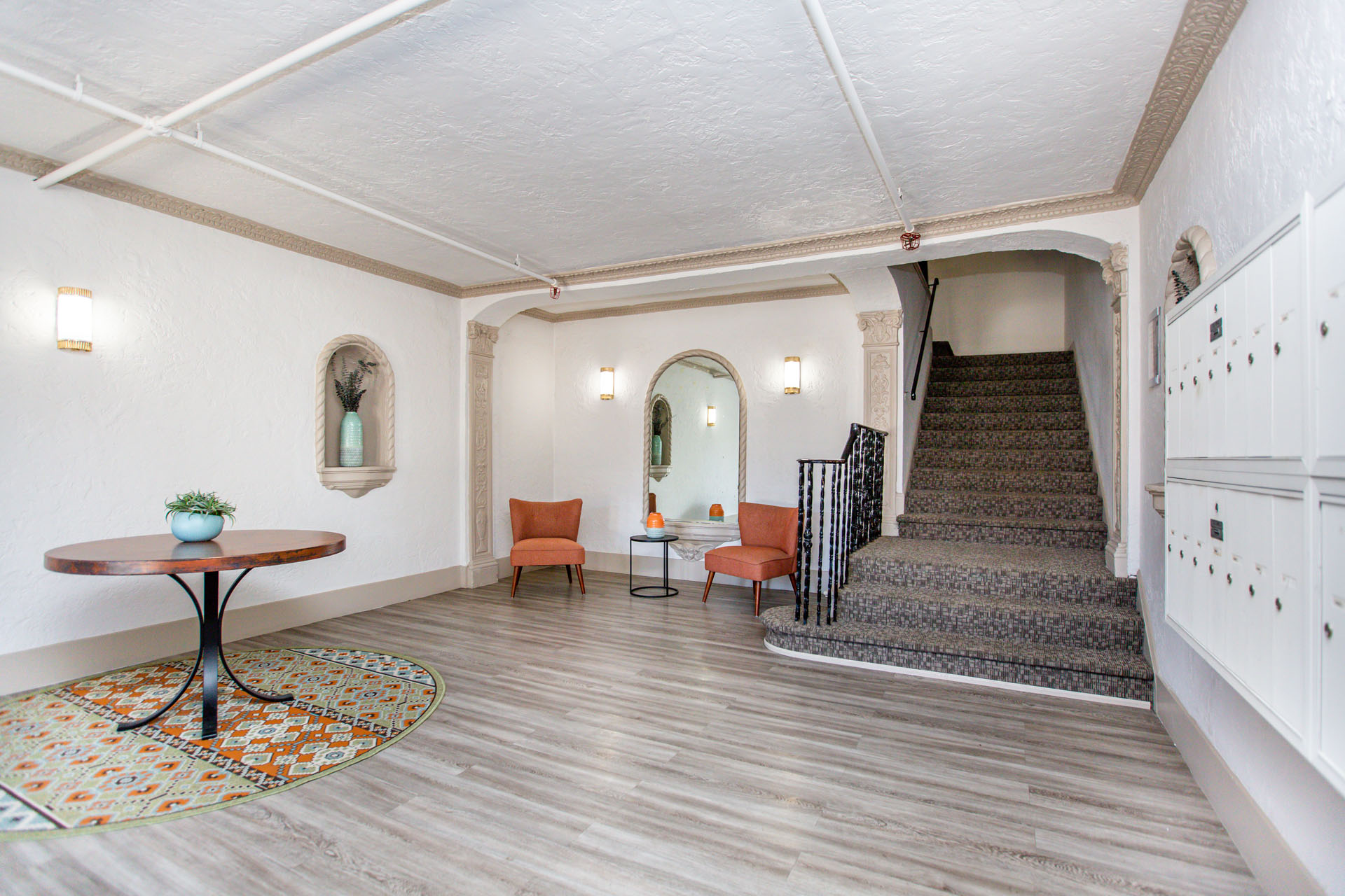 A hallway with a staircase, a table, and chairs.