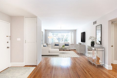 A living room with a white couch and a wooden floor.