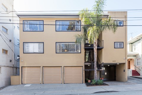 A tan building with a palm tree in front.