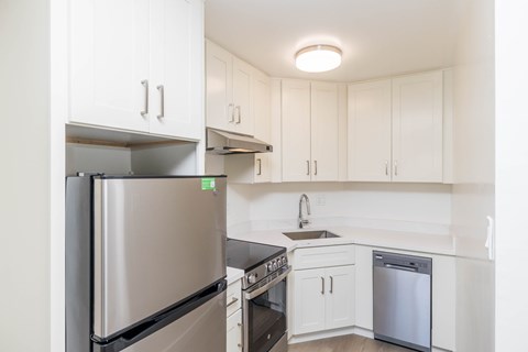 A kitchen with white cabinets and a stainless steel refrigerator.