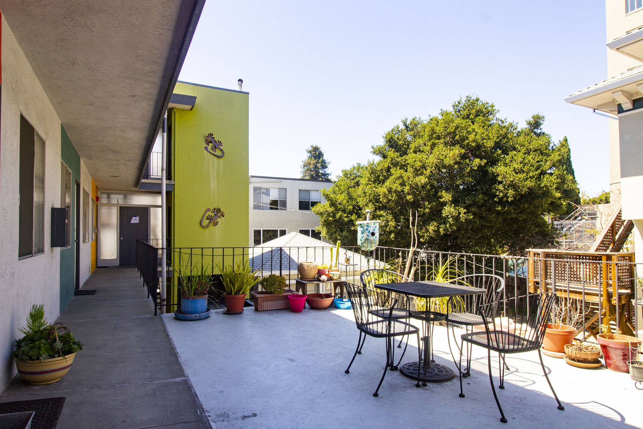 A patio with a table and chairs and a green tree.