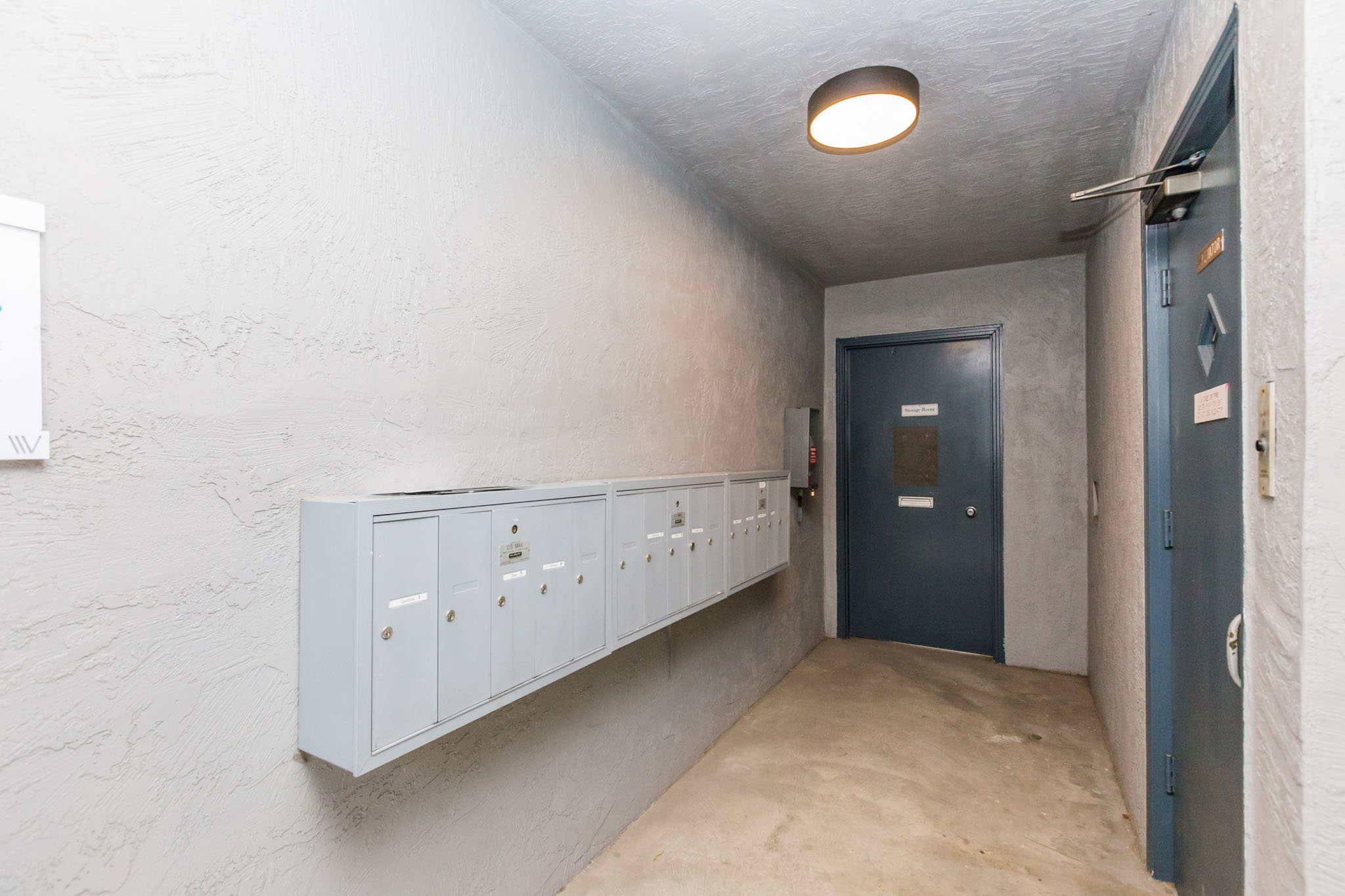 A hallway with a blue door and white walls.