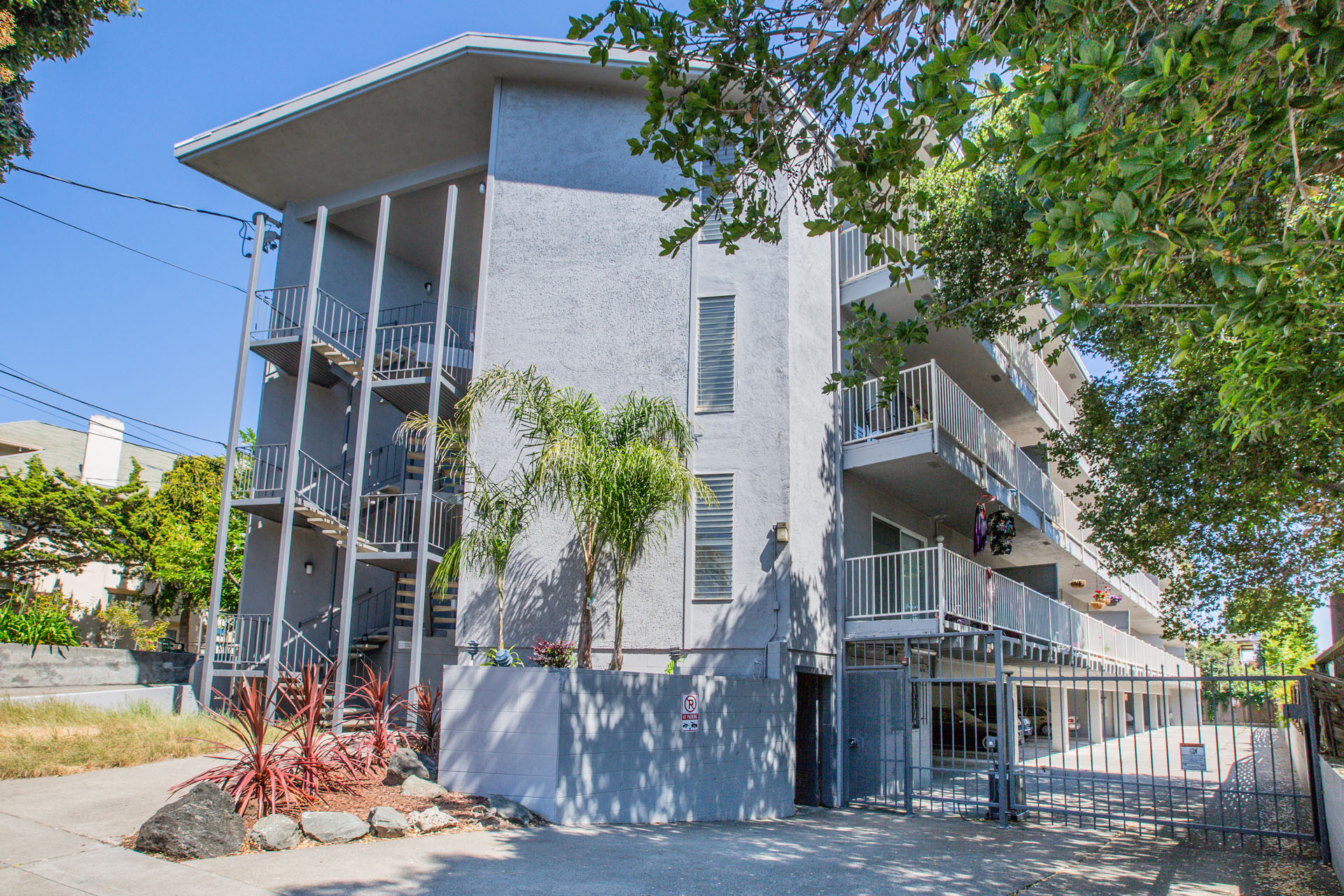 A white building with balconies and a gate in front.