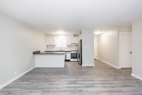 A kitchen with white cabinets and a wooden floor.