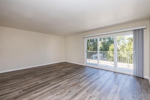 an empty living room with wood flooring and sliding glass doors