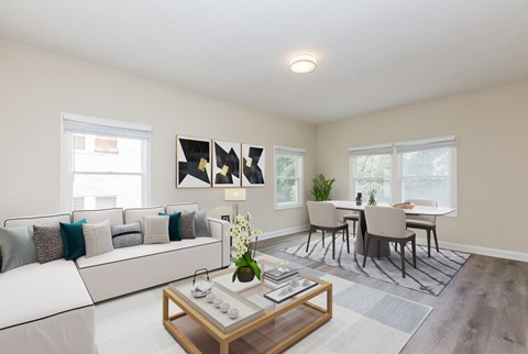 A modern living room with a white sofa, a coffee table, and a dining table with chairs.